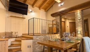 a dining room with a wooden table and a television at Paradiso di Grosio - mansarda con vista montagne in Grosio +3 photos
