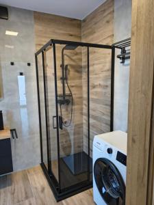 a washer and dryer in a bathroom with a shower at Domki nad jeziorem in Dobczyce
