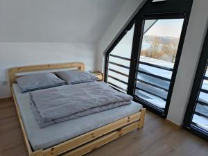 a bedroom with a bed and a large window at Domki nad jeziorem in Dobczyce