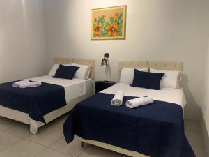 2 Betten in einem blau-weißen Zimmer in der Unterkunft 103-Quarto Pousada HG in Vila Nova do Sul