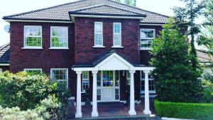 a red brick house with a white front porch at Balally House in Shannon