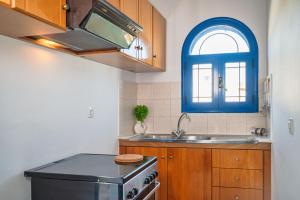 een keuken met een wastafel en een blauw raam bij Anna's view Stegna in Vrachonisída touArchangélou +16 foto's
