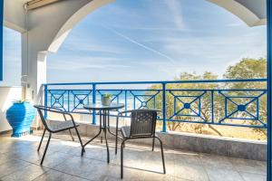 een tafel en stoelen op een balkon met uitzicht op de oceaan bij Anna's view Stegna in Vrachonisída touArchangélou