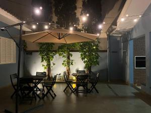 ein Esszimmer mit Tisch, Stühlen und einem Sonnenschirm in der Unterkunft Flow Pousada in Maringá