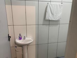 ein weiß gefliestes Bad mit einem Waschbecken und einem Handtuch in der Unterkunft 103-Quarto Pousada HG in Vila Nova do Sul