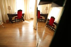 ニュルンベルクにあるホテル ドライ ラーベンの赤い椅子と窓付きのテーブルが備わる客室です。