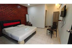 ein Schlafzimmer mit einem Bett, einem Fernseher und einem Stuhl in der Unterkunft Hotel O Classic Homestay Keningau in Keningau