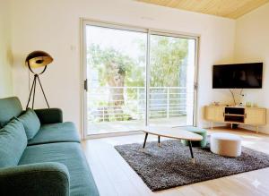 a living room with a blue couch and a table at Cottage Les Ormeaux - à 13 minutes du Puy du Fou in Les Herbiers
