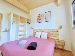 a bedroom with a pink bed with a wooden headboard at Cottage Les Ormeaux - à 13 minutes du Puy du Fou in Les Herbiers