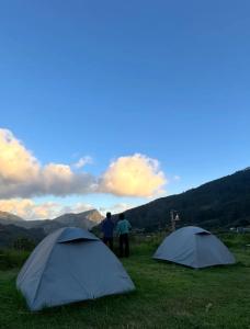 Twee mensen staan naast twee tenten in een veld. bij Misty Colina in Kottakamboor