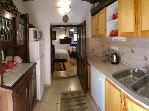 a kitchen with a sink and a refrigerator and a bedroom at Natura Vendégház in Pázmánd