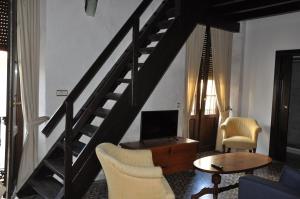 a living room with a staircase with chairs and a table at Casa de las Remigias in Estepona
