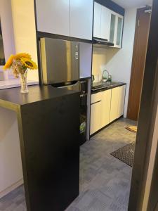 een keuken met een zwarte koelkast en een vaas met bloemen bij Fave apartment Nagoya Thamrin in Nagoya