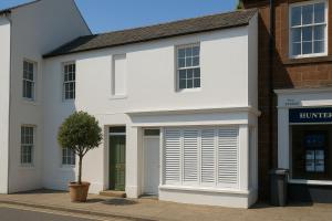 une maison blanche avec un arbre devant dans l'établissement Bridge View Cottages, à Annan