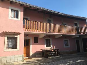 a pink house with a wooden balcony and a picnic table at Kraska hisa in Komen