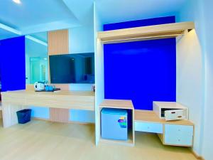 a room with a blue wall with a tv at Armoni Patong Beach Hotel in Patong Beach