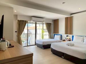 a hotel room with two beds and a balcony at Armoni Patong Beach Hotel in Patong Beach