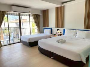 a hotel room with two beds and a balcony at Armoni Patong Beach Hotel in Patong Beach