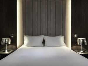 a large white bed with two lamps on both sides at Sofitel Athens Airport in Athens +136 photos