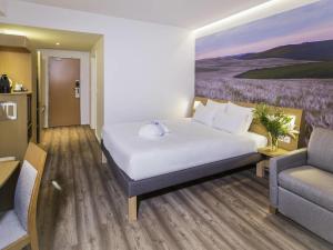 een hotelkamer met een bed, een bank en een stoel bij Novotel Sevilla in Sevilla