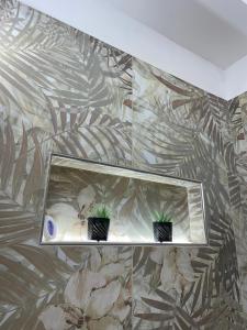 une chambre avec deux plantes sur un mur dans l'établissement Salinelle Home, à Paterno