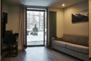 ein Wohnzimmer mit Sofa und Glasschiebetür in der Unterkunft Hotel Europa in Breuil-Cervinia