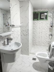een witte badkamer met een wastafel en een toilet bij Everest Lounge in Abu Dhabi