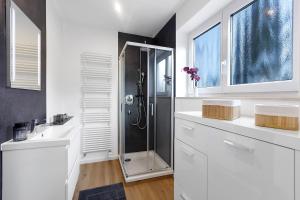 een witte badkamer met een douche en 2 wastafels bij Hivent Ferienwohnungen in Bad Dürrheim +41 foto's