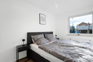 een bed in een witte kamer met een raam bij Hivent Ferienwohnungen in Bad Dürrheim