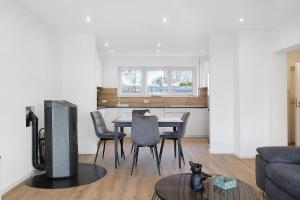 een woonkamer met een tafel, stoelen en een televisie bij Hivent Ferienwohnungen in Bad Dürrheim