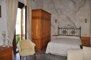 a bedroom with a bed and a cabinet and a chair at Casa de las Remigias in Estepona