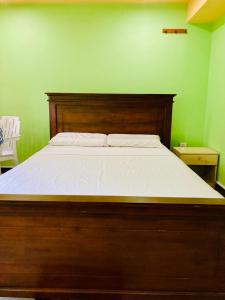 a bed in a green bedroom with a wooden headboard at New Verona Hotel in Wennappuwa