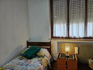 een slaapkamer met een bed en een tafel met een lamp bij La Casa di Sandhya in Udine