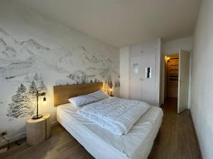 ein Schlafzimmer mit einem Bett mit einem Wandbild der Berge in der Unterkunft BEC452- Superbe 2 pièces, vue Lac - Tignes in Tignes