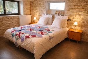 una camera da letto con un letto con una trapunta sopra di La Verrière du May a Sancy-le-Bas