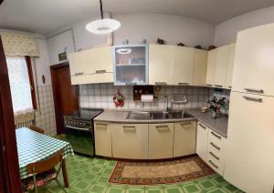 - une cuisine avec des placards blancs, un évier et une table dans l'établissement Casa nella campagna Toscana, à Lazzeretto