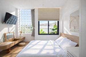 ein Schlafzimmer mit Bett, Schreibtisch und Fenster in der Unterkunft Adory Homestay Huế in Hue