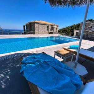 een zwembad met een tafel en een parasol bij Villa Dolihi in Agios Kirykos