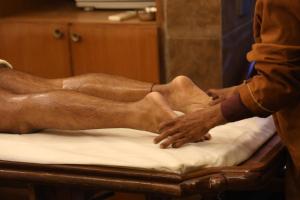 Ein Mann, der sich auf einem Bett die Füße massieren lässt in der Unterkunft Essence of Nature, Ranikhet in Rānīkhet