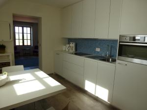 a kitchen with white cabinets and a sink and a table at B&B 't Hof van Spiere in Spiere