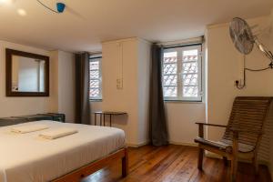 een slaapkamer met een bed, een stoel en ramen bij WOT New Lisbon Social in Lissabon +94 foto's