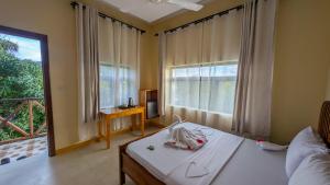 a room with a bed and a window and a table at Joujo's Jungle Guest House in Nungwi