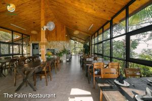 een eetkamer met tafels en stoelen en ramen bij TVpalm Ecolodge in Ha Giang
