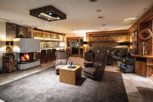 een lobby met een open haard en stoelen en een bar bij Hotel Garni Alpenjuwel in Serfaus