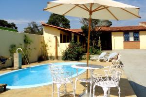 a table with an umbrella next to a pool at Pousada Luz do Sol in Carrancas +37 photos
