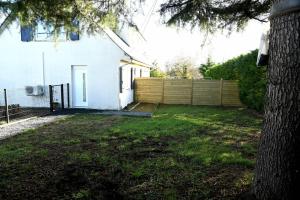 a yard with a white house and a fence at Confortable studio avec jardin in Saint-Doulchard