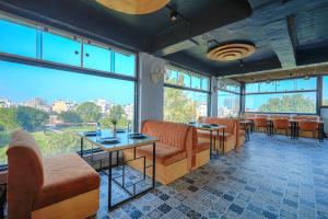 ein Restaurant mit Tischen und Stühlen und großen Fenstern in der Unterkunft Hotel Global Inn in Amritsar