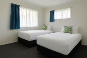 2 bedden in een hotelkamer met blauwe gordijnen bij Pure Motel in Rotorua