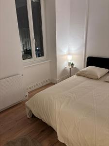 een witte slaapkamer met een bed en een raam bij Le Parisien - Cœur de Saint-Brieuc in Saint-Brieuc