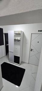 een witte kamer met een koelkast en een spiegel bij Tina apartman in Vranje +2 foto's